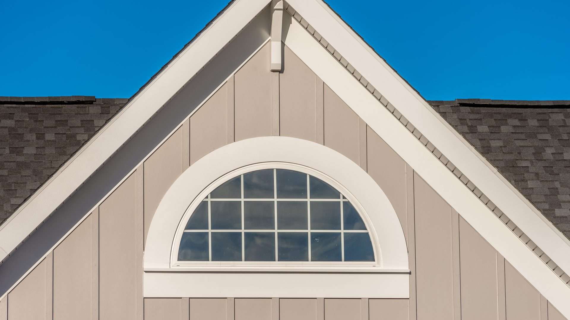 Home with beige siding and half-circle window in Bridgehampton, NY