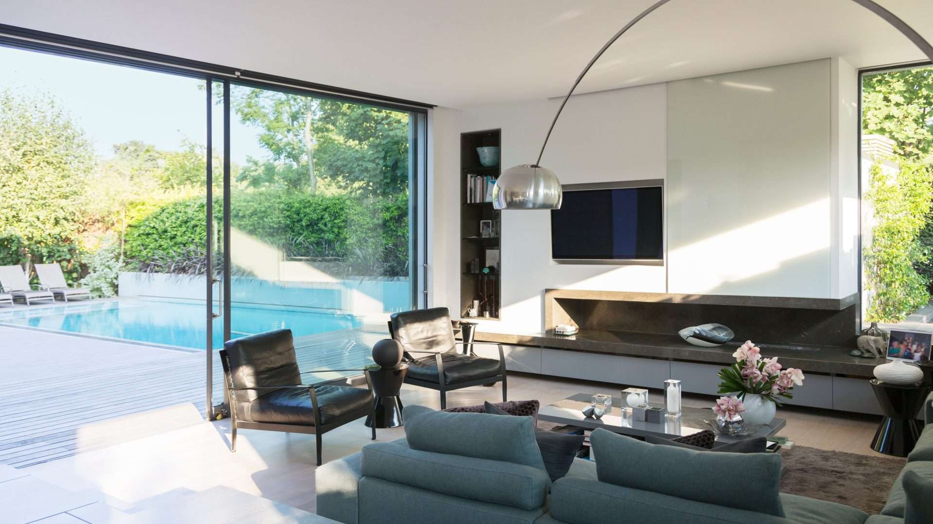 Interior view of an open, minimal-frame aluminum door overlooking a patio and pool
