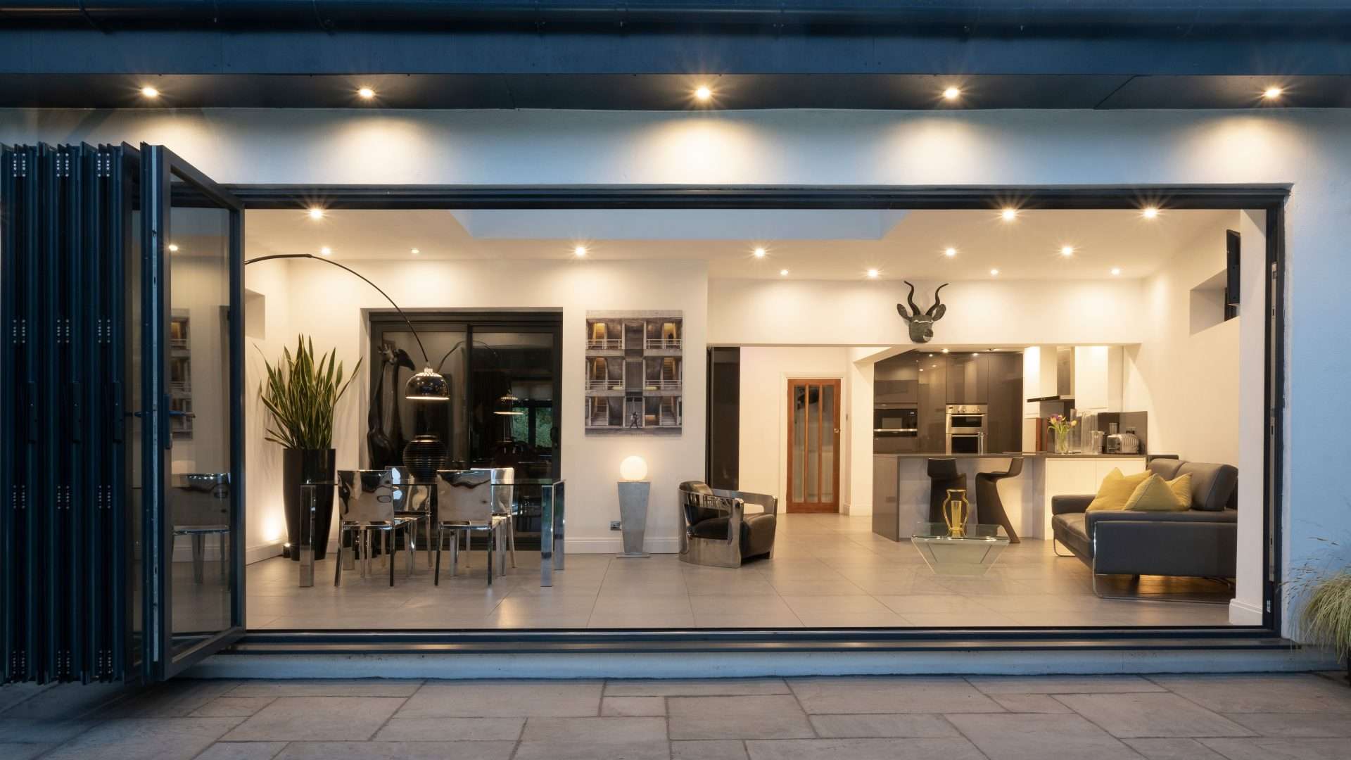 Exterior view of an open, wall-length aluminum door in a modern home