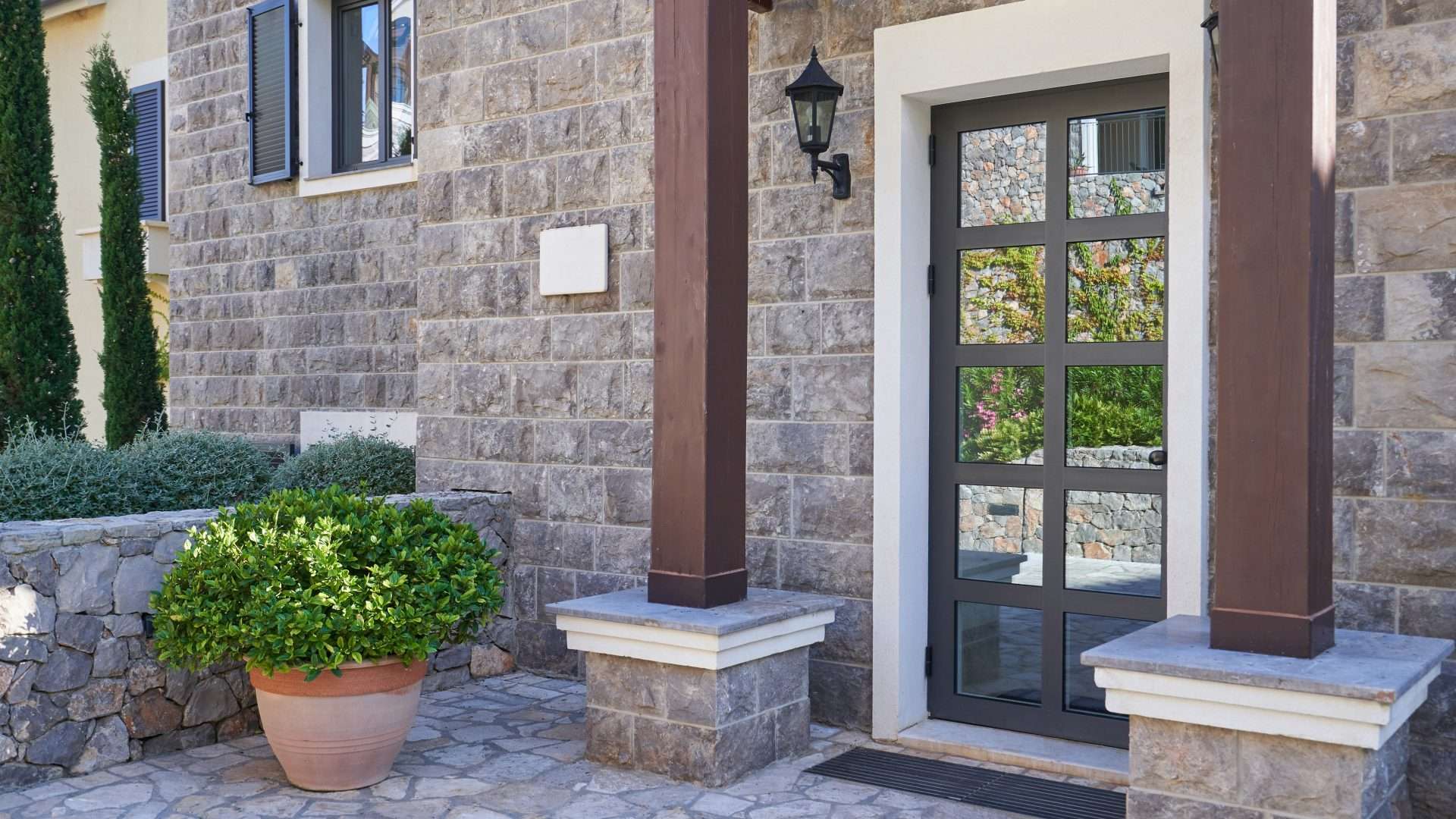 Close view of a grey stone house with an aluminum front door