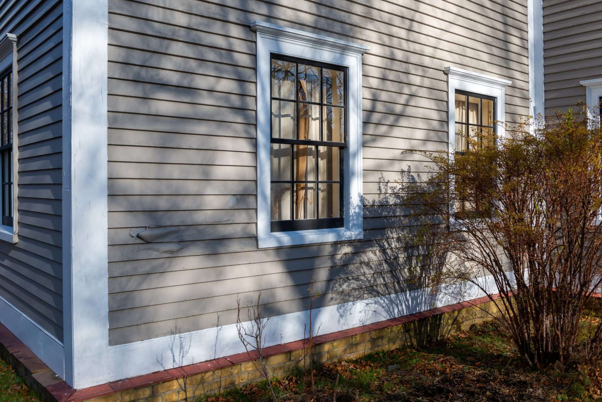 Outside a pair of new double-hung windows against beige house siding