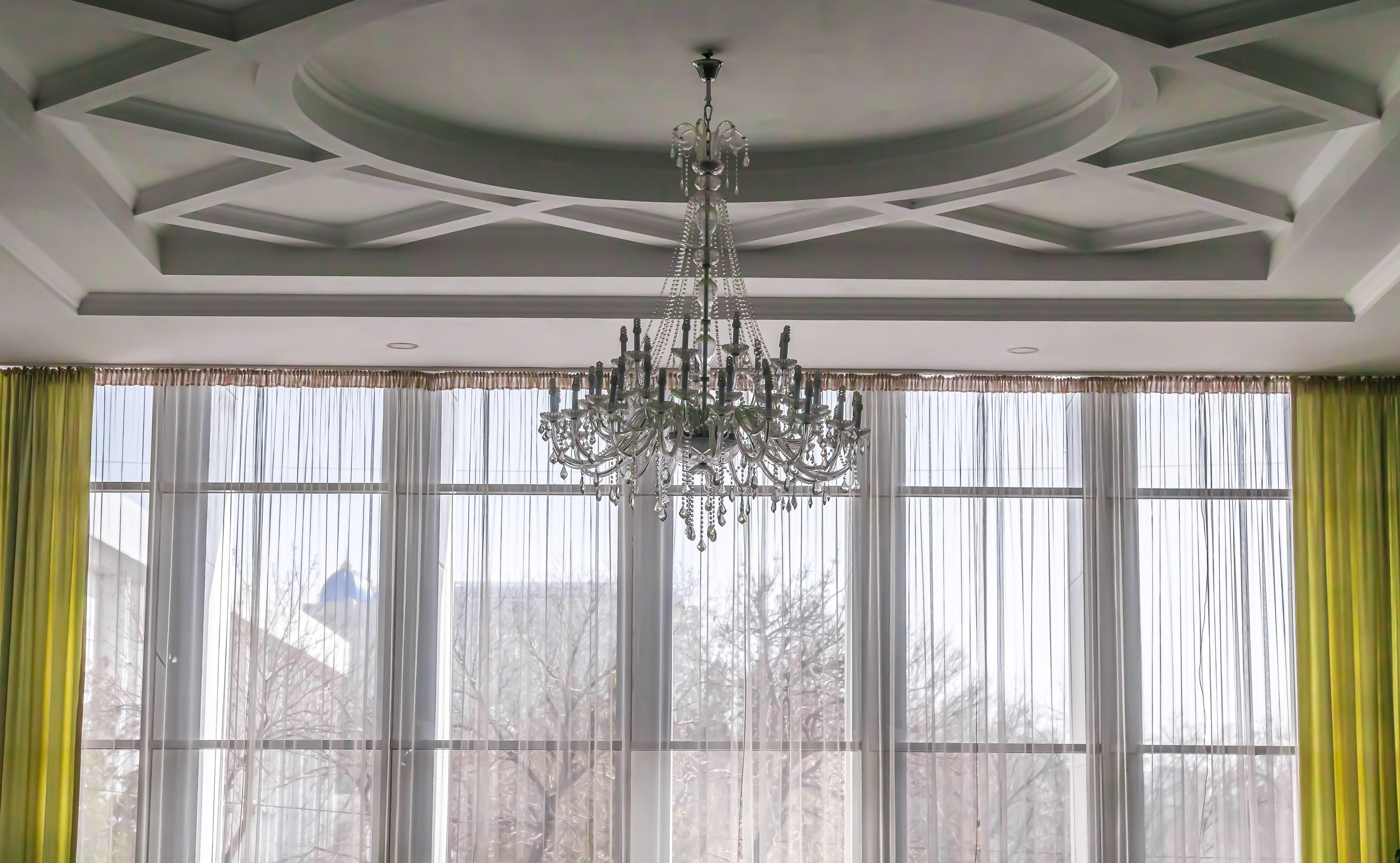 Custom Windows For Scarsdale, NY Homes | Rockman Windows & Doors A Scarsdale, NY luxury home featuring a large room with custom windows and translucent curtains with a chandelier hanging from ceiling.
