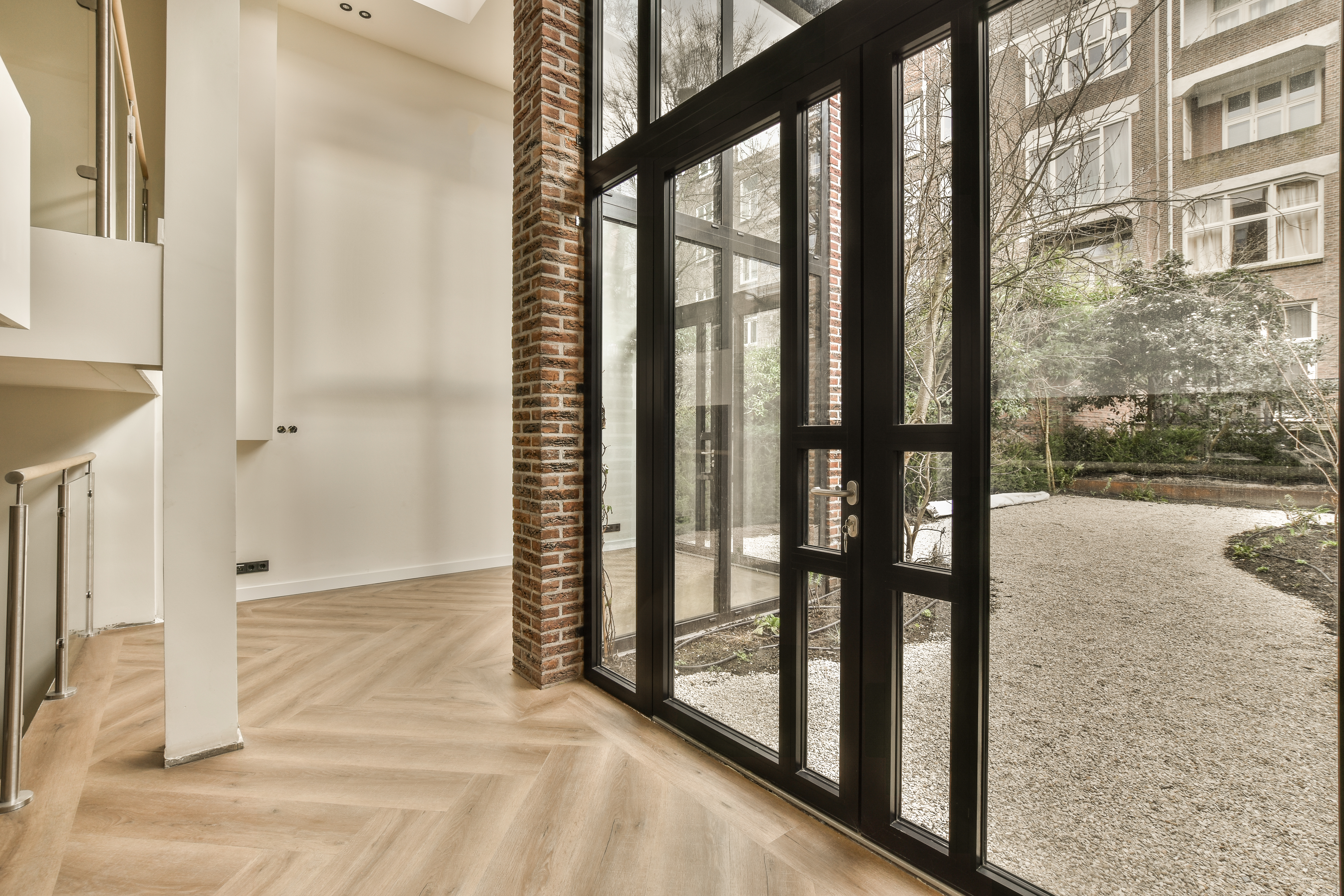 Gorgeous Entry Doors in Rye, NY | Rockman Windows & Doors A tall glass door with black metal frames overlooking a courtyard.