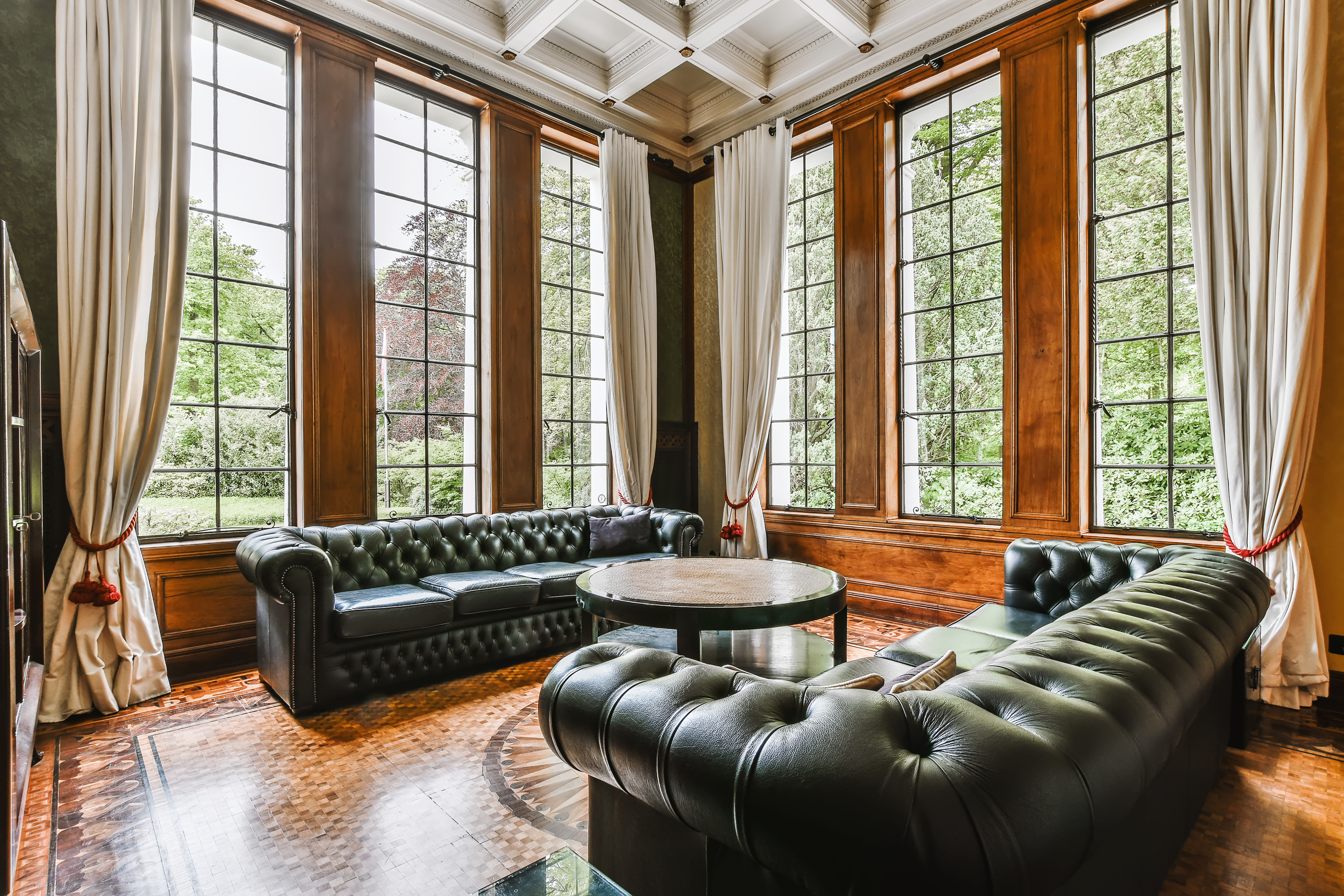 Durable Windows In Scarsdale, NY | Rockman Windows And Doors A stylish living room with leather couches, a circular table, and tall windows with curtains.