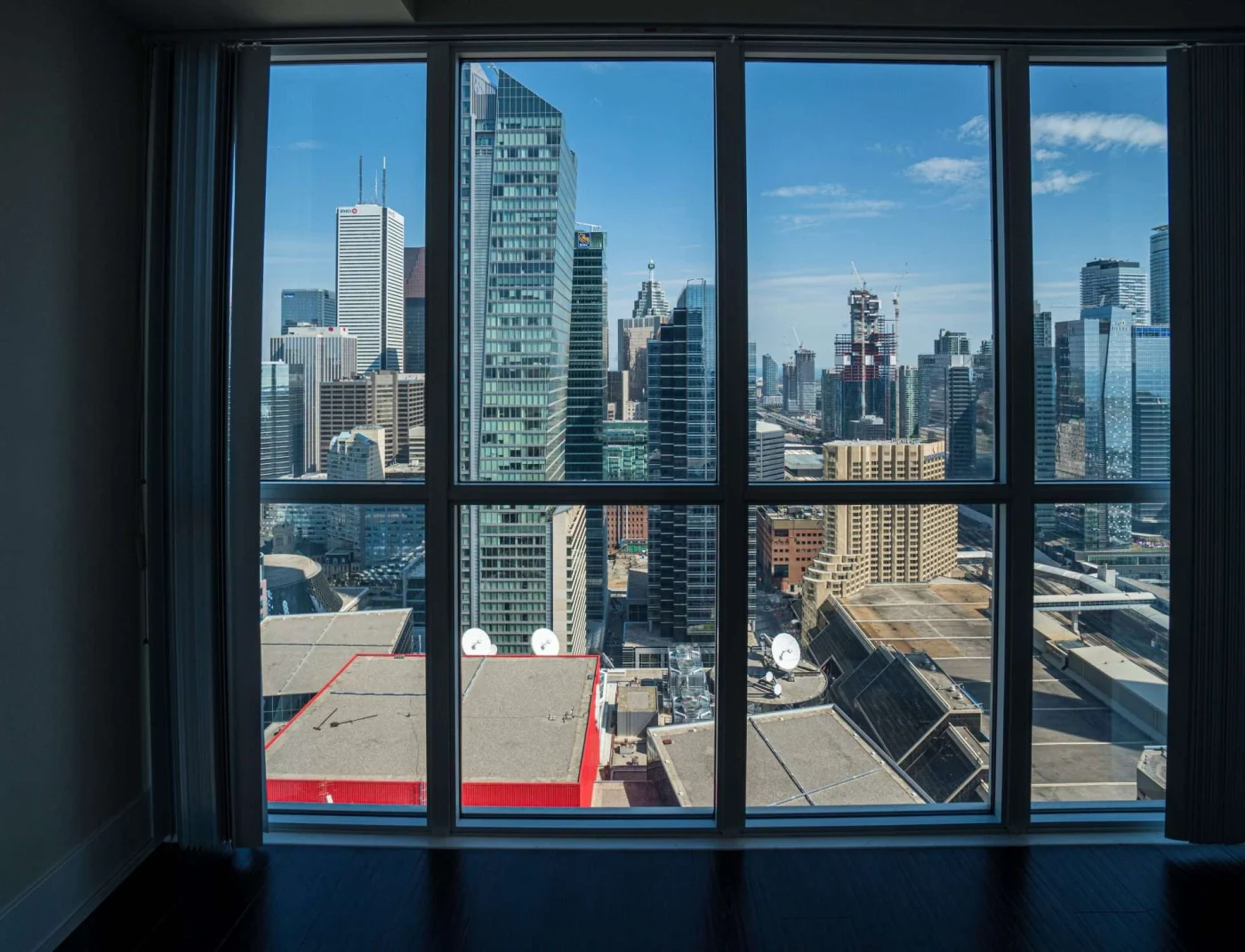 Incredible Aluminum Windows | Greenwich, CT | Rockman Windows and Doors Floor-to-ceiling aluminum windows frame a city skyline with glass towers, rooftops, blue sky, vertical blinds, and dark wood flooring.